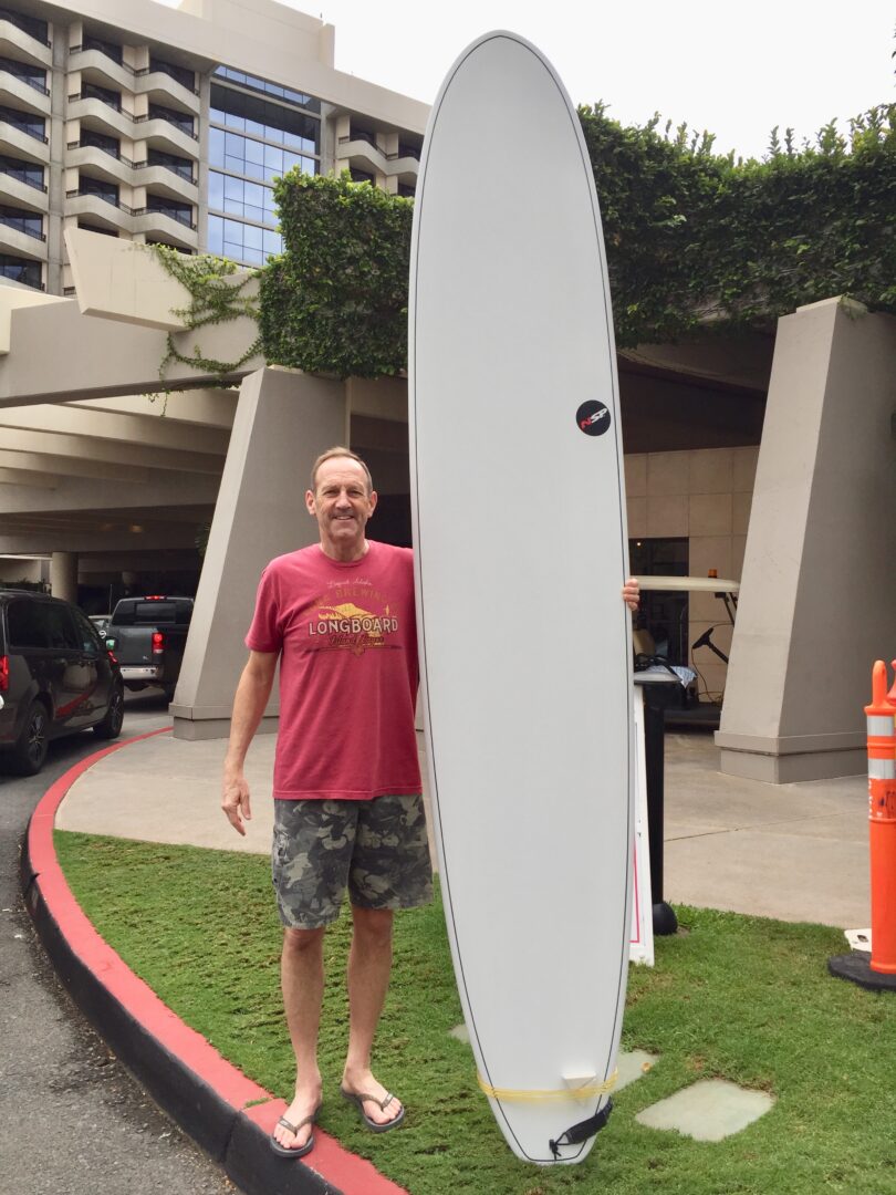 A man standing next to a surfboard in front of a building.