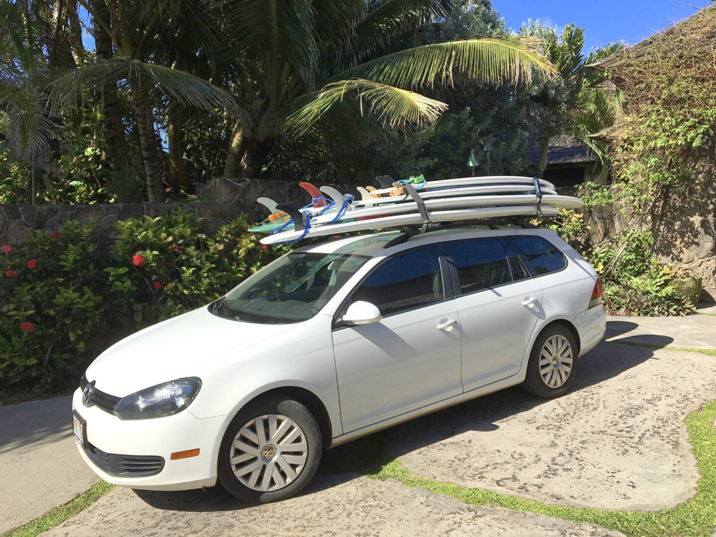 A white car with surfboards on top of it.