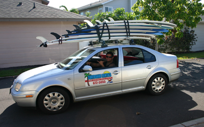 A car with two surfboards strapped to the roof.