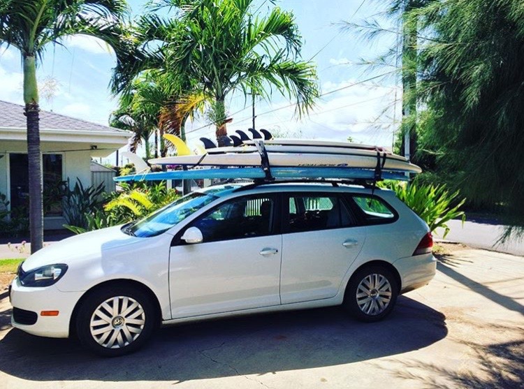 A white car with two surfboards on top of it.