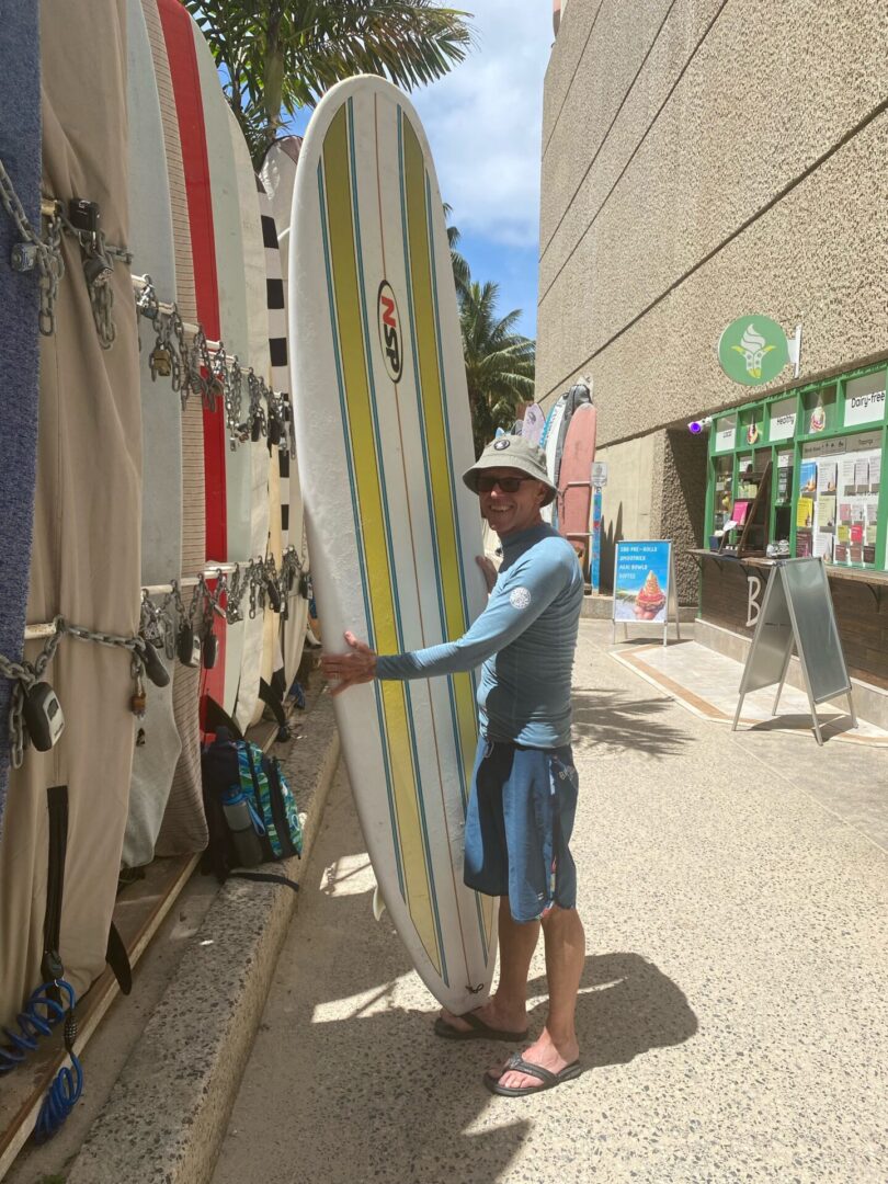 A man holding a surfboard in front of a store.